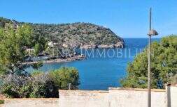 Panoramablick auf die Bucht von Port de Sóller mit Leuchtturm, türkisblauem Meer und bewaldeter Halbinsel