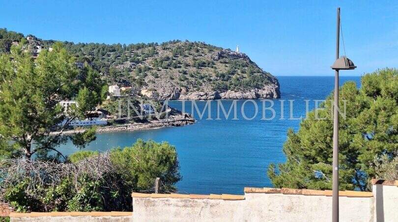 Panoramablick auf die Bucht von Port de Sóller mit Leuchtturm, türkisblauem Meer und bewaldeter Halbinsel