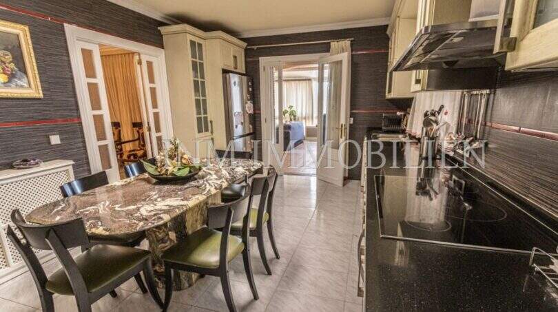 Küche mit Esstisch aus Marmor, schwarzen Einbaugeräten und Zugang zum Wohnbereich in Villa Marratxí