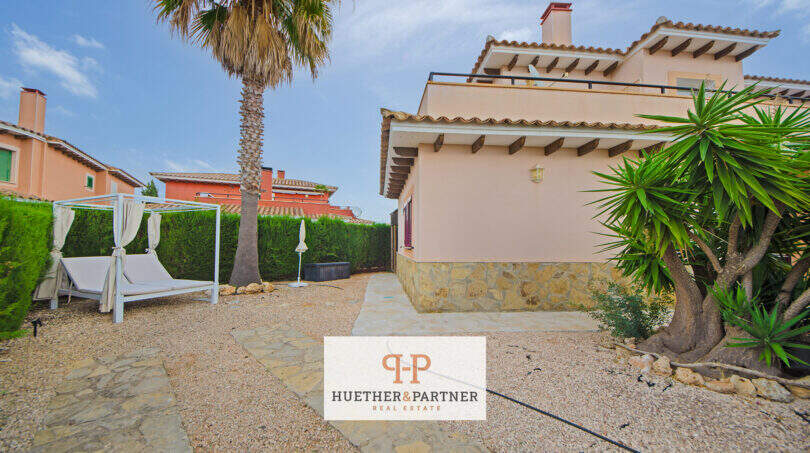 Außenbereich eines Hauses in Cala Murada mit Kiesgarten, Palmen, Loungebett-Pavillon und mediterraner Steinfassade.
