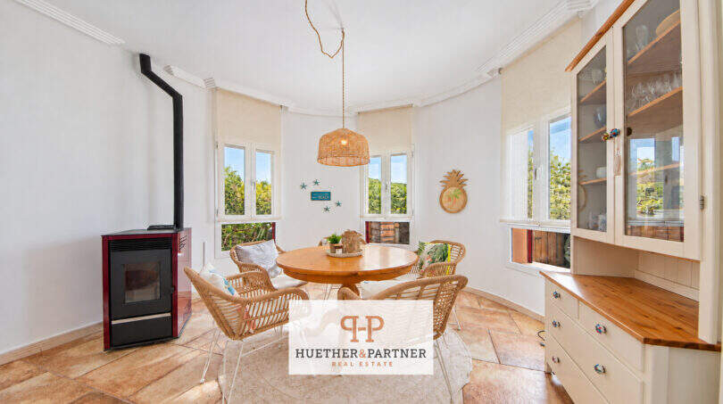 Helles Esszimmer mit rundem Holztisch, Korbstühlen, Pelletofen und Vitrine im Haus in Cala Murada