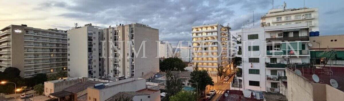 Abendlicher Blick vom Balkon über die Dächer von El Arenal, Palma de Mallorca, mit belebter Straße und Stadtpanorama.