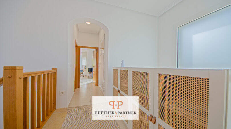 Heller Treppenflur mit Holzgeländer, Rattanschrank und Bogendurchgang in Haus in Cala Murada