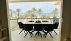 Glazed terrace with dining table, 8 chairs and direct sea view of Palma's beach with palm trees