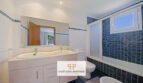 Modernes Badezimmer der Mallorca-Wohnung mit Doppelwaschbecken, blauer Fliesendusche und Badewanne.