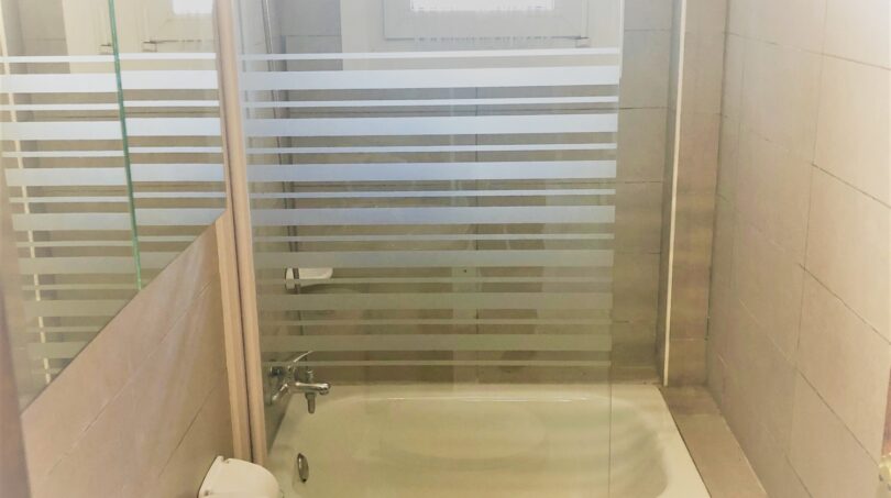 Helles Badezimmer der Mietwohnung in Cala Ratjada mit Badewanne, Glasabtrennung, WC und Waschbecken