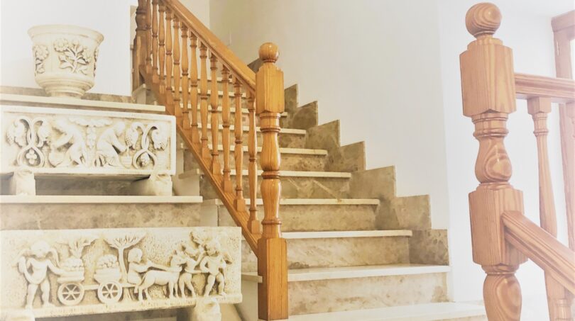 Elegante Marmortreppe mit Holzgeländer und Reliefverzierungen im Treppenhaus der Mietwohnung in Cala Ratjada