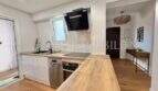 Moderne weiße Einbauküche mit Holzarbeitsplatte, Induktionskochfeld und Dunstabzug in renovierter Wohnung Palma