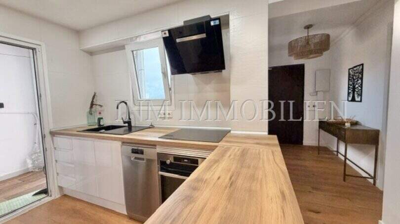 Moderne weiße Einbauküche mit Holzarbeitsplatte, Induktionskochfeld und Dunstabzug in renovierter Wohnung Palma