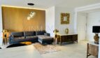 Elegant living room of the designer apartment in Palma with velvet sofa, wooden panel wall and gold accents.