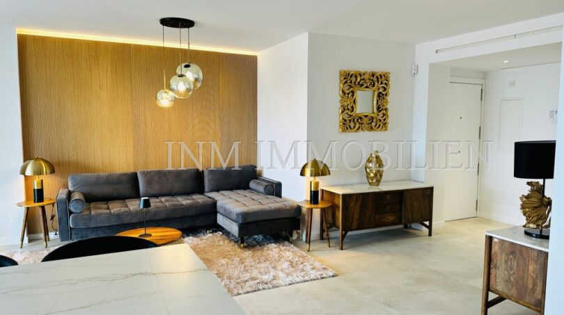 Elegant living room of the designer apartment in Palma with velvet sofa, wooden panel wall and gold accents.