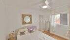 Helles Schlafzimmer der renovierten Wohnung in Ses Cadenes mit Doppelbett, Deckenventilator und Parkettboden.
