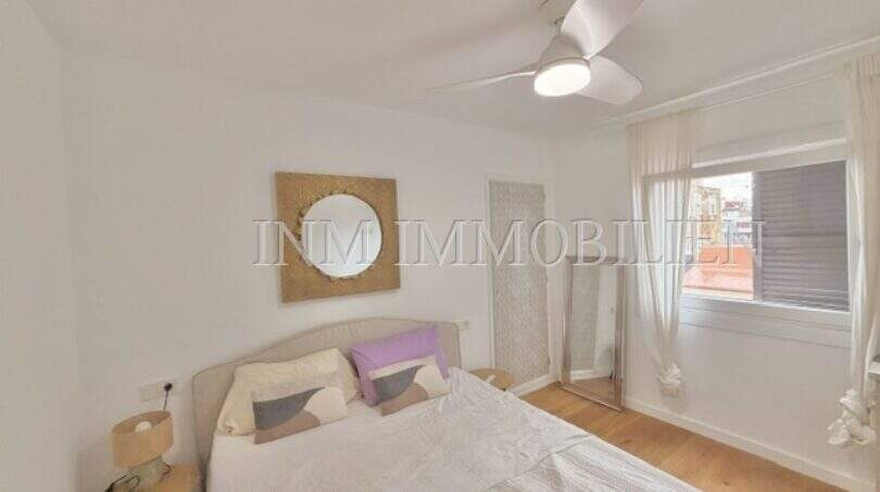 Helles Schlafzimmer der renovierten Wohnung in Ses Cadenes mit Doppelbett, Deckenventilator und Parkettboden.