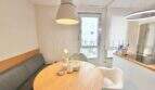 Helle Essecke mit rundem Holztisch, grauer Eckbank und modernen Hängeleuchten in Maisonette-Wohnung, Palma