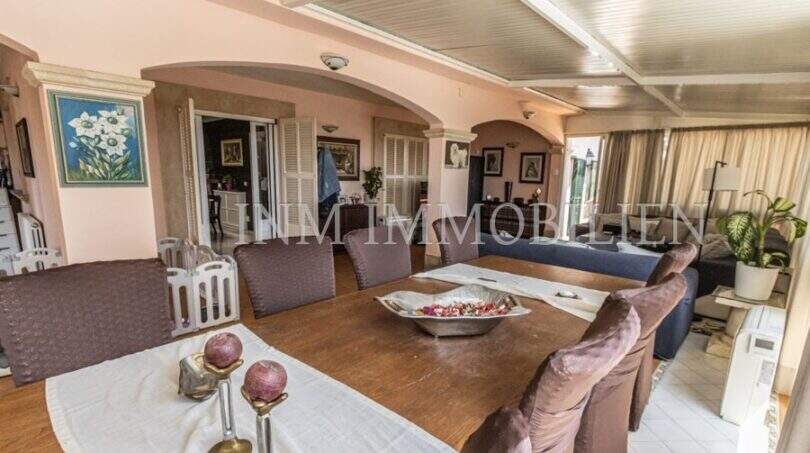 Geräumiges Wohn-Esszimmer der Villa in Marratxí mit Holztisch, Bogendurchgängen und rosa Wänden.
