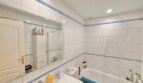 Helles Badezimmer mit weißen Fliesen, blauem Dekorstreifen, Badewanne und Waschtisch im Reiheneckhaus Pollença