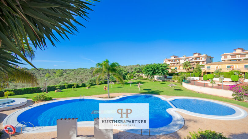Gemeinschaftspool mit Liegewiese und mediterrane Wohnanlage in Cales de Mallorca, umgeben von Grünflächen