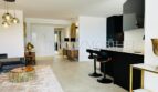 Open living-kitchen area with black designer kitchen, bar stools, gold accents and modern interior in Mallorca designer apartment