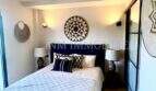 Schlafzimmer des Penthouses mit Doppelbett, Deckenventilator und dekorativen Wandelementen im Boho-Stil