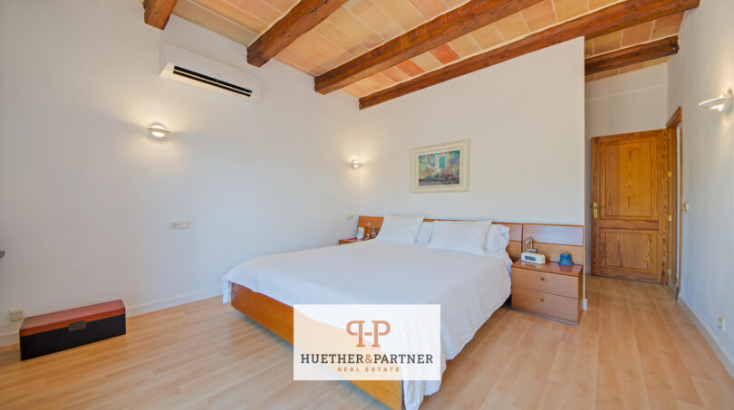 Dormitorio luminoso de la finca Felanitx con cama doble, techo de vigas de madera y aire acondicionado