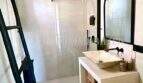 Modernes Badezimmer im Penthouse Playa de Palma mit Regendusche, Naturstein-Waschtisch und schwarzen Designelementen.