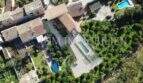 Vista aérea finca rústica en Sóller con techos de terracota, piscina, jardín y exuberante vegetación mediterránea.