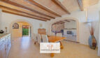 Helles Esszimmer der Finca Felanitx mit Holzbalkendecke, Natursteinwand und Kamin