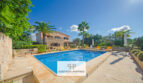 Finca Felanitx: Piscina mediterránea con terraza de piedra natural, palmeras y casa de campo rústica bajo cielo azul