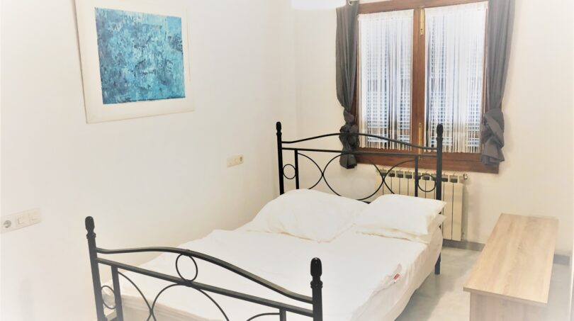 Helles Schlafzimmer der Mietwohnung in Cala Ratjada mit Doppelbett, blauem Wandbild und Fenster