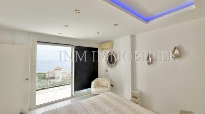 Helles Schlafzimmer mit indirekter LED-Beleuchtung, Meerblick-Terrasse und modernem Design im Penthouse Cala Pi.