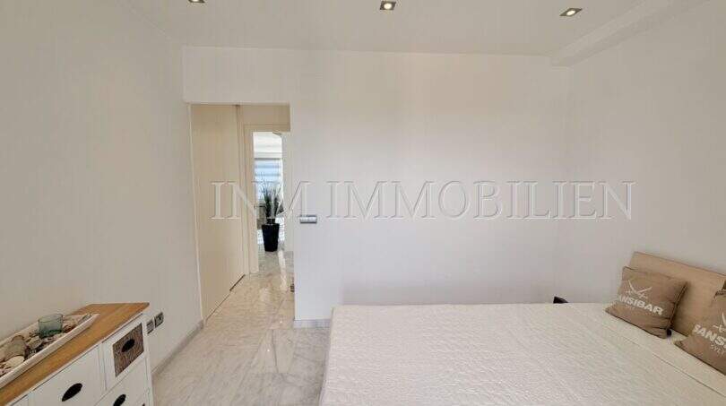 Helles Schlafzimmer mit weißen Wänden, Marmorboden, Einbaustrahlern und Doppelbett im Penthouse Cala Pi.
