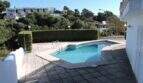 Außenbereich der Ferienvilla in Cala Mandia mit privatem Pool, Terrasse und Grünhecke mit Meerblicklage.