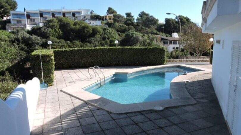 Außenbereich der Ferienvilla in Cala Mandia mit privatem Pool, Terrasse und Grünhecke mit Meerblicklage.