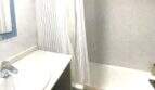 Luminoso baño con bañera, cortina de ducha y lavabo en apartamento vacacional moderno en Alcudia