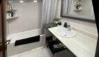 Luminoso baño con bañera, cortina de ducha, espejo grande y lavabo blanco cerca del mar, Alcudia