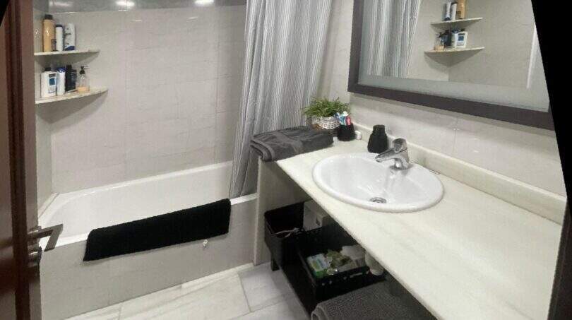 Luminoso baño con bañera, cortina de ducha, espejo grande y lavabo blanco cerca del mar, Alcudia