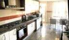 Espaciosa cocina con estufa de gas, horno empotrado, frentes blancos y zona de comedor adyacente con acceso al balcón en Alcudia