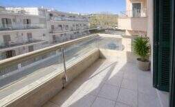Sonniger Balkon mit Glasgeländer und Blick auf Nachbargebäude in moderner Meeresnähe-Wohnung in Alcúdia