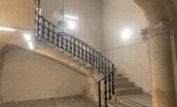 Escalera histórica con escalera de piedra curva, barandilla de hierro forjado y arco abovedado en la casa urbana de Llucmajor
