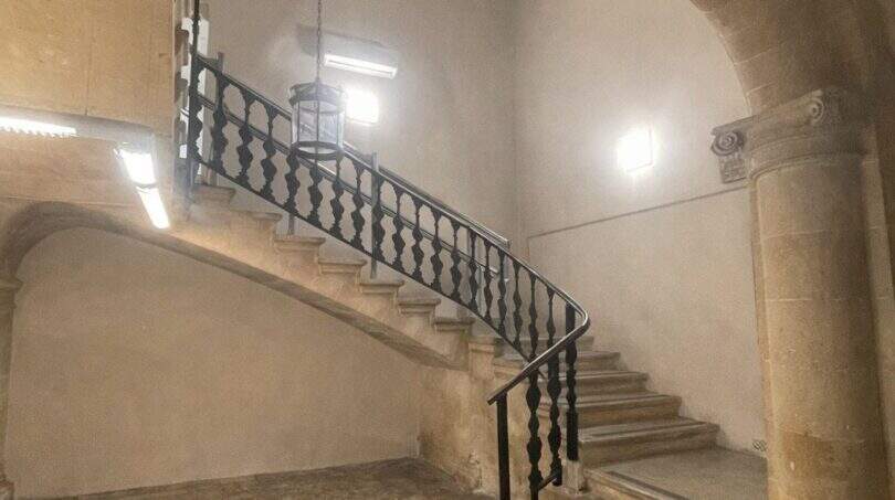 Escalera histórica con escalera de piedra curva, barandilla de hierro forjado y arco abovedado en la casa urbana de Llucmajor
