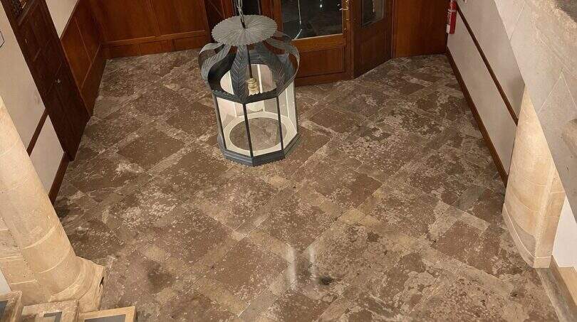 Entrada histórica con suelo de piedra, arco de medio punto, puertas de madera y linterna colgante en la casa urbana de Llucmajor