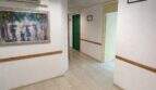 Pasillo luminoso con suelos de baldosa, moldura de madera, cuadro y puerta verde en la casa urbana de Llucmajor