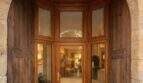 Entrada elegante con arco de medio punto de piedra natural, puerta de madera y cristaleras de una casa urbana en Llucmajor