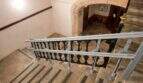 Escalera de piedra histórica con barandilla de hierro forjado y pasamanos moderno en la casa urbana de Llucmajor