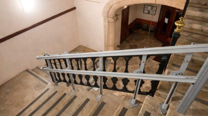 Escalera de piedra histórica con barandilla de hierro forjado y pasamanos moderno en la casa urbana de Llucmajor