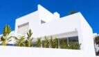 Moderne weiße Designvilla in Portixol mit Dachterrasse, Glasgeländer und tropischen Pflanzen unter blauem Himmel
