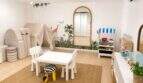 Helles Kinderspielzimmer mit Dschungel-Wandmalerei, Spielküche, Kuschelecke und weißen Möbeln in der Designvilla.