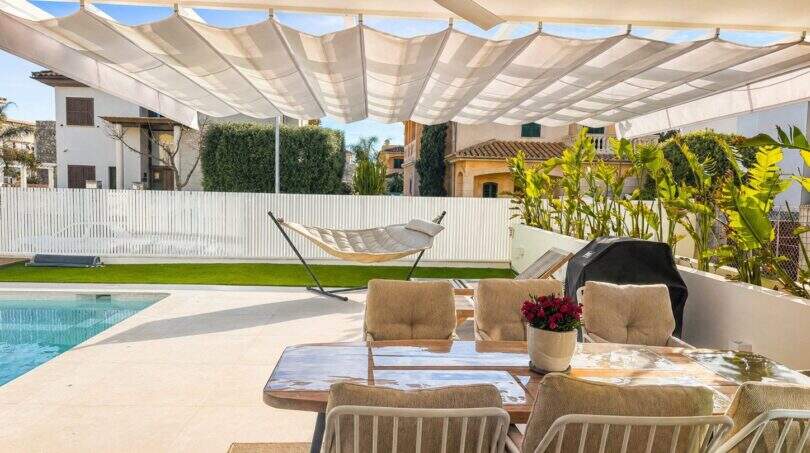 Überdachte Poolterrasse der Designvilla in Portixol mit Esstisch, Hängematte und Grill