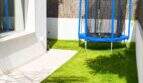 Kleiner Garten der Designvilla in Portixol mit gepflegtem Rasen und blauem Trampolin