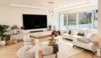 Helles Wohnzimmer der Designvilla in Portixol mit weißen Sofas, Parkettboden und großen Fenstern zum Garten.